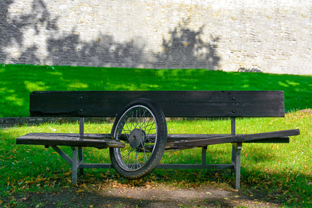 Wooden bench in the park. Motorcycle wheel stuck in the bench. Motorbike accident with a bench. Broken boards after accident.の写真素材