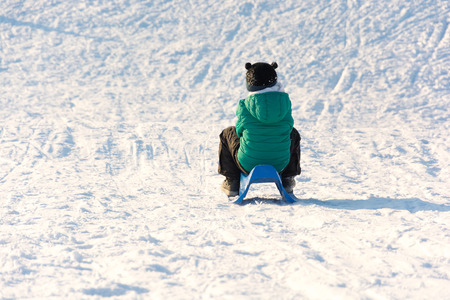 Boy playing in the snow. Sledding on a snowy hill. Winter games. Baby joy of snow. Throwing snowballs.の写真素材