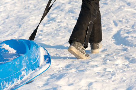 Boy playing in the snow. Sledding on a snowy hill. Winter games. Baby joy of snow. Throwing...