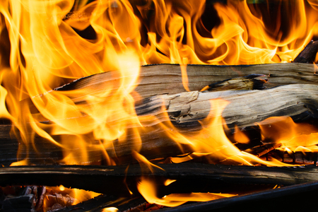 Burning wooden log covered with red fire. Grilled fire in the barbecue. Dangerous for burns....