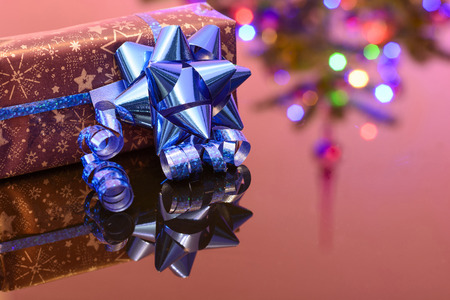 Christmas gift wrapped in purple wrapping paper bound with blue ribbon and ornamentの写真素材