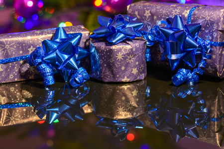 Christmas gifts wrapped in purple wrapping paper bound with blue ribbon and ornamentの写真素材