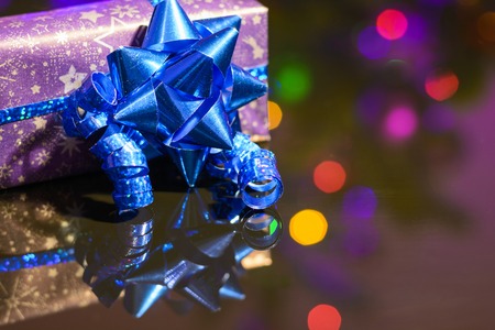 Christmas gift wrapped in purple wrapping paper bound with blue ribbon and ornamentの写真素材