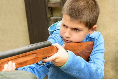 A little boy shooting from an air rifle to a targetの写真素材