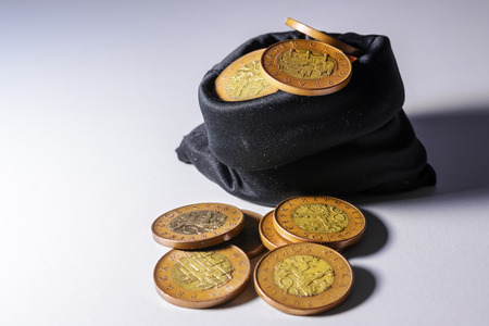 Czech gold coins in a black bag on a white background. Detail of spent coins. Savings in small...