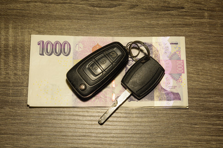 The concept of selling and buying a car. Car keys laid on Czech banknotes. Money to repair the car. Financial concept.の写真素材