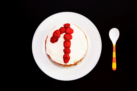Sweet birthday cake with strawberries and number one on a white plate. Cake as a gift to your first birthday. の写真素材