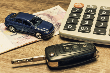 Car keys, banknotes, car model, and calculator as the concept of buying or renting a car. Loan for buying a car. Czech money at the table. Financial concept with money.の写真素材