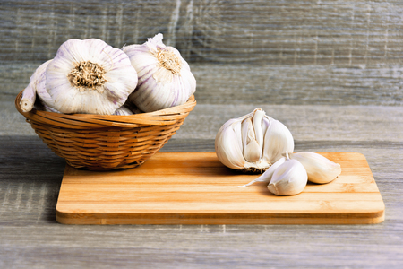 Garlic and garlic cloves on a wooden cutting board. Product photo of garlic. Healthy lifestyle. Source of antioxidants and vitamins. Vegetarian and vegan diet.の写真素材