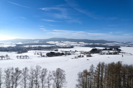 Winter landscape with snow covered fields and village in the distance, Kraliky, Czech Republicの写真素材