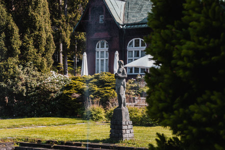 Karlova Studanka, Czech republic - 27.5.2023: Spa building with stone sculpture behind the bushのeditorial素材