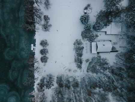Dramatic winter drone view of frozen lake and forest with abandoned cottage, Svitavy, Czechia