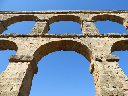 Detail of the arches of Pont del Diable Aqueduct in Tarragona Spain shot from below with a bright blue sky backgroundの写真素材