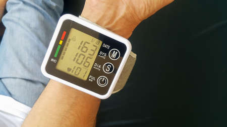 Measure your blood pressure at home using a portable device to check Your health. The device shows a high pressure value.の写真素材