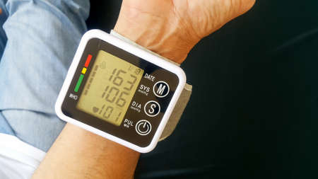 Measure your blood pressure at home using a portable device to check Your health. The device shows a high pressure value.の写真素材