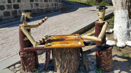 Gyumri, Shirak region / Armenia-September 1, 2020.two people from a tree are playing backgammon. Wooden doll. Table games. The concept of games. Figures of a man made of wood.のeditorial素材
