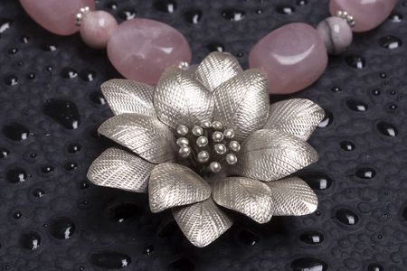 A bead necklace with flower pendant on black background
