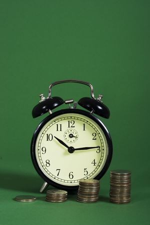 A row on coins with increasing value with an alarm clock