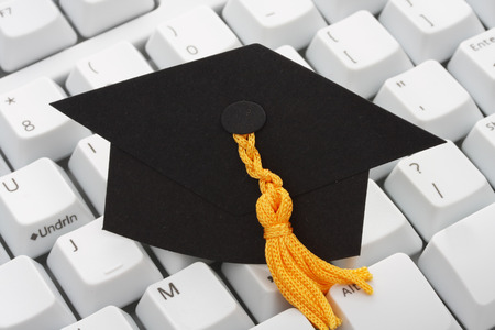 A  black graduation cap on a keyboard backgroundの写真素材
