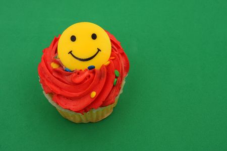 Cupcake with happy face on green backgroundの写真素材