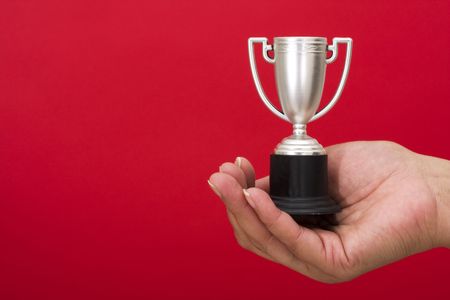 Trophy in hand on red background with copy spaceの写真素材