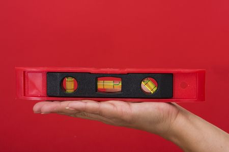 Level on hand with a red backgroundの写真素材