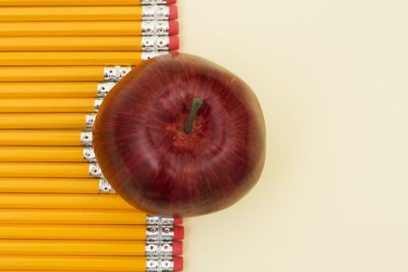 Pencils lined in a row with apple with copy space