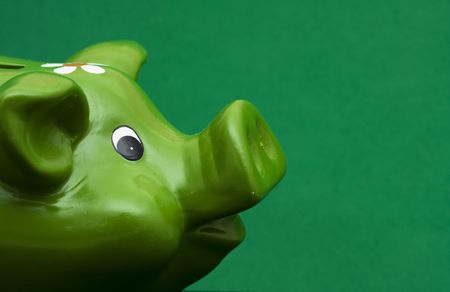 Green piggy bank on green background with copy spaceの写真素材