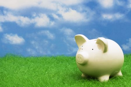 Coin bank sitting on grass with copy spaceの写真素材