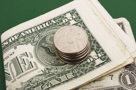 Stack of dollar bills with coins on a green background