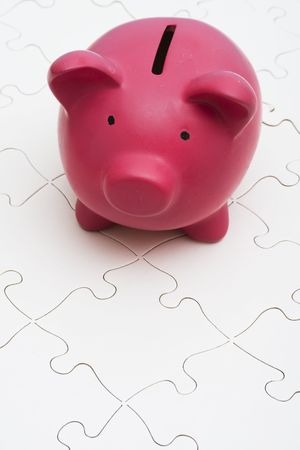 Piggy bank sitting on puzzle, understanding the ins and outs of investingの写真素材