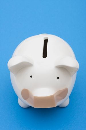 Piggy bank with adhesive bandage on mouth on blue background, investment troubleの写真素材