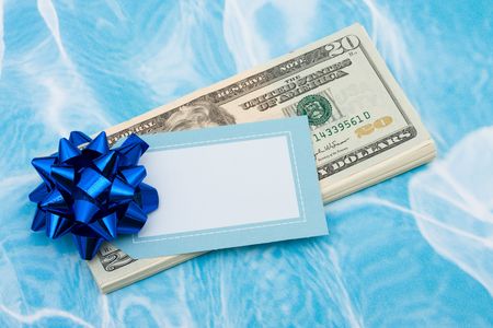 Twenty dollar bills with red bow on them and a blank gift tag on blue background, gift of money