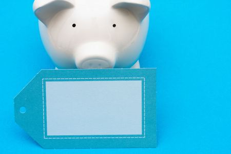 Piggy bank with blank tag on blue background with copy space, savings interest rateの写真素材