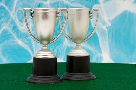 Two trophies on green with blue backgroundの写真素材