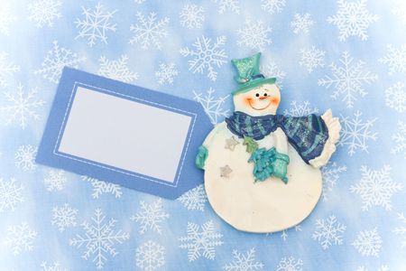 Snowman with blank gift tag on snowflake background, merry Christmasの写真素材