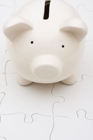 Piggy bank sitting on white puzzle, understanding personal financesの写真素材