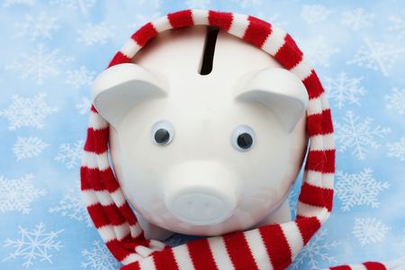 Piggy bank wearing a scarf on snowflake background, Christmas savingsの写真素材
