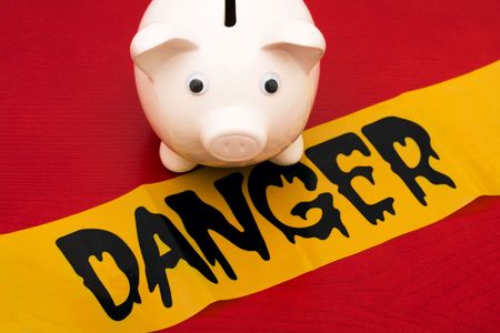 Pink piggy bank with danger tape on red background, dangerous investmentsの写真素材