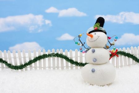 Snowman and white picket fence with green garland and red bow, merry Christmasの写真素材