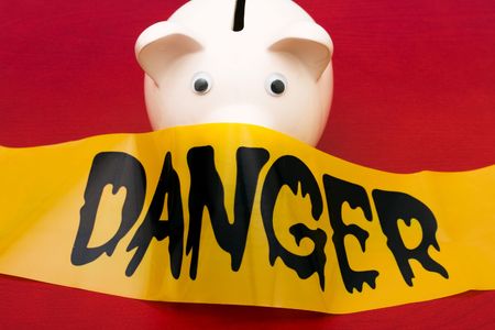 Pink piggy bank with danger tape on red background, dangerous investmentsの写真素材