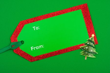 Christmas tree with blank green gift tag on green background – holiday gift