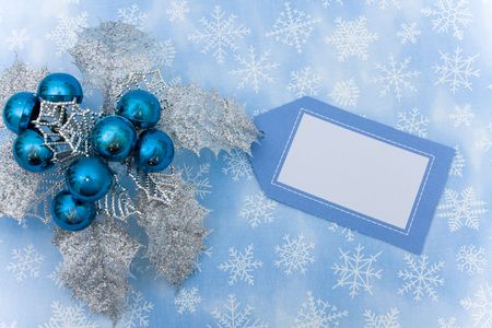 Silver leaves and blue berries with blank gift tag on snowflake background, Christmas decorationの写真素材