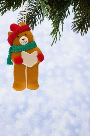 Teddy bear ornament hanging from a tree on snowflake backgroundの写真素材