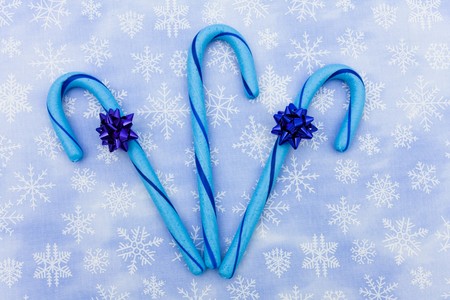 Blue candy canes with bow sitting on a blue snowflake background, candy canesの写真素材