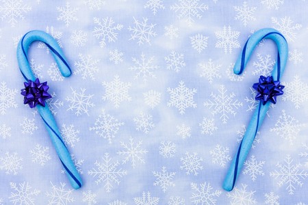Blue candy canes with bow sitting on a blue snowflake background, candy canesの写真素材