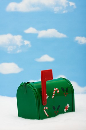 Green mailbox with candy canes and holly leaves and berries with the flag up sitting on snow with a snowflake background, mailboxの写真素材