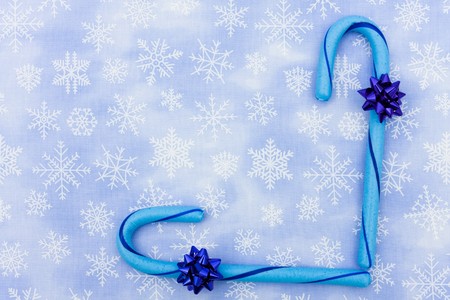 Blue candy canes with bow sitting on a blue snowflake background, candy canesの写真素材