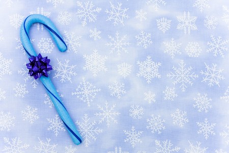 Blue candy cane with bow sitting on a blue snowflake background, candy caneの写真素材