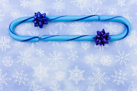 Blue candy canes with bow sitting on a blue snowflake background, candy canesの写真素材